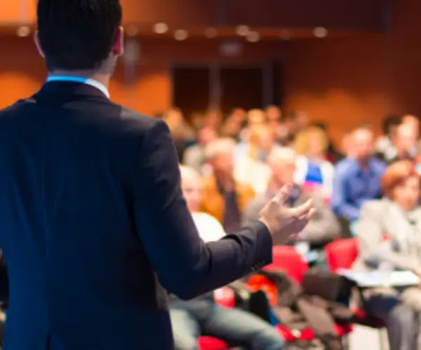 A speaker addressing an international audience in a conference room